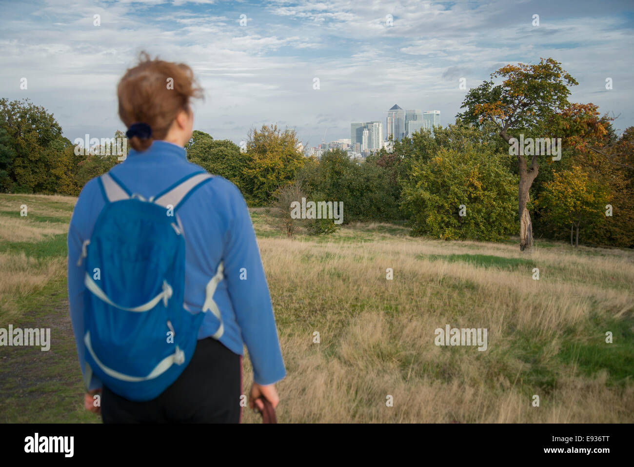 Female hiker looking over the view of Canary Wharf, London Docklands, from Greenwich Park. October 2014 Stock Photo