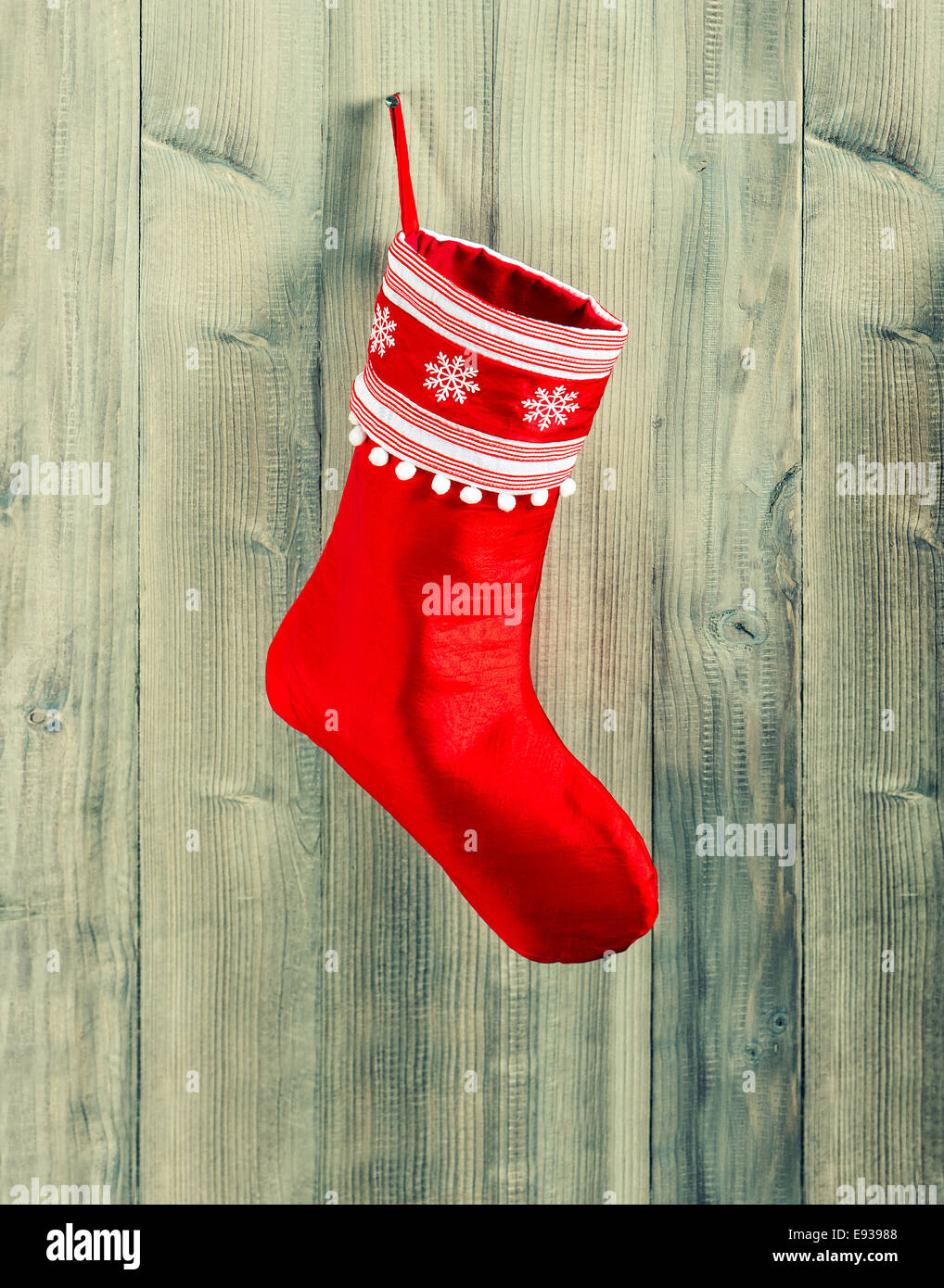 christmas stocking. red sock with white snowflakes hanging over rustic wooden background Stock Photo