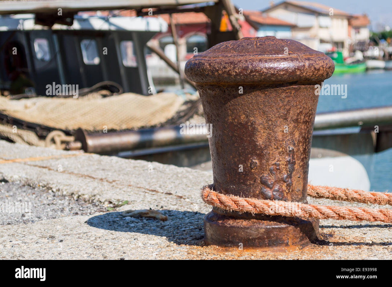 old bollard with rope mooring and boats in the background Stock Photo