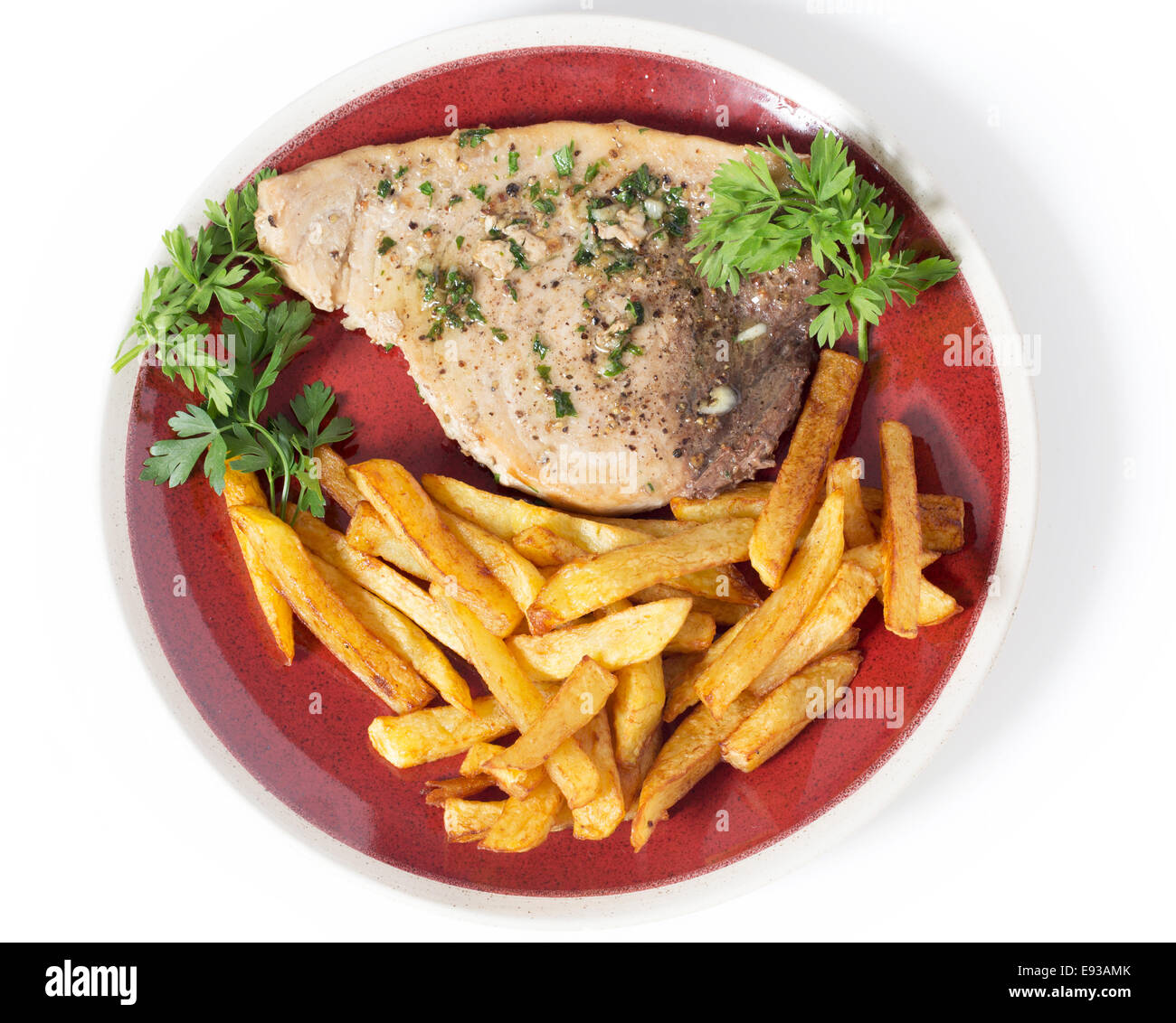 Swordfish steak cooked on a plate with french fries and a parsley and