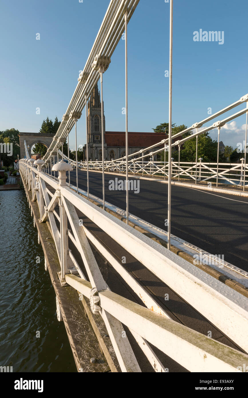 detail of old suspension bridge on  river Thames , shot in bright light with All Saints church in background Stock Photo