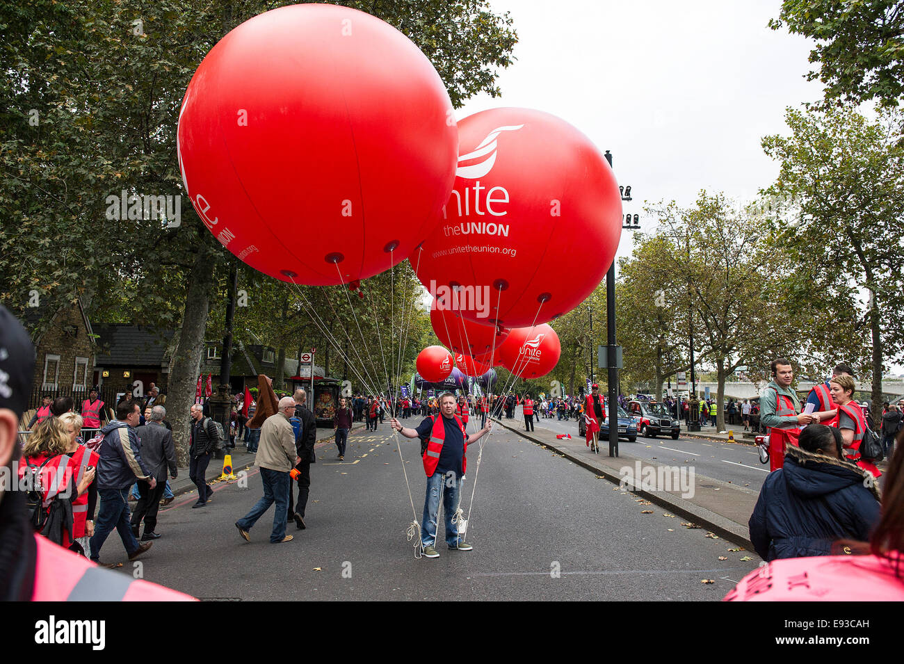 London, UK. 18 October 2014. 'Britain Needs A Payrise'   A TUC national demonstration in Central London.  A member of UNITE  trade union holds onto large balloons as the march prepares to set off from the Embankment. Photo: Gordon Scammell/Alamy Live News Stock Photo