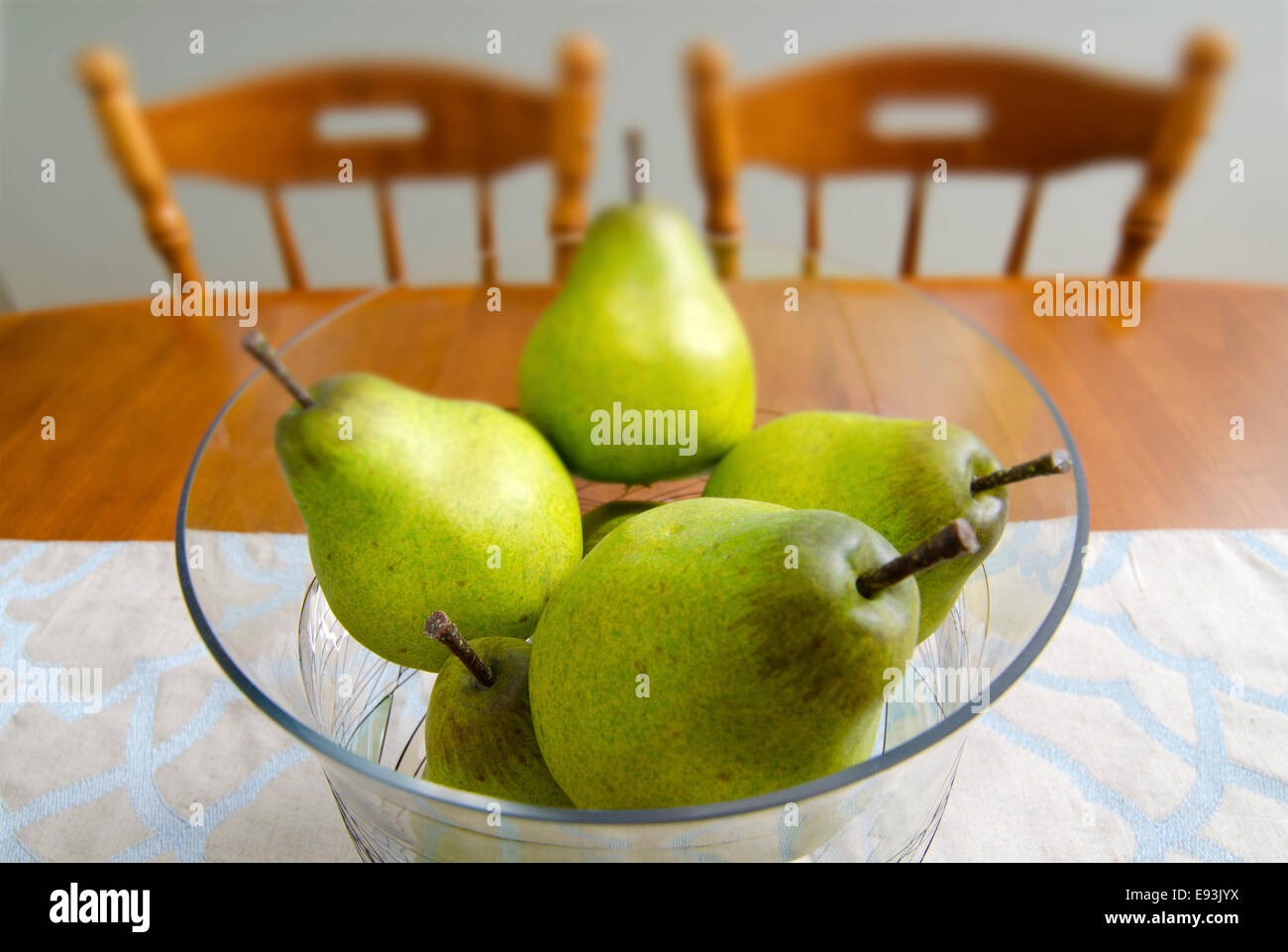 Pears are placed in a decorative bowl and used as a centerpiece on a dining room table. Stock Photo