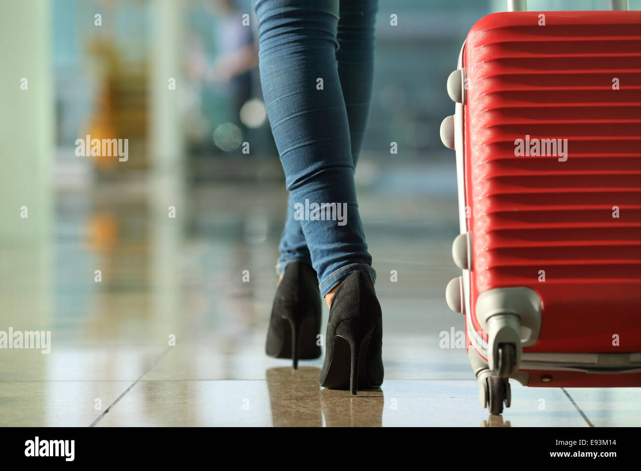 Traveler woman legs walking carrying a suitcase in an airport Stock Photo