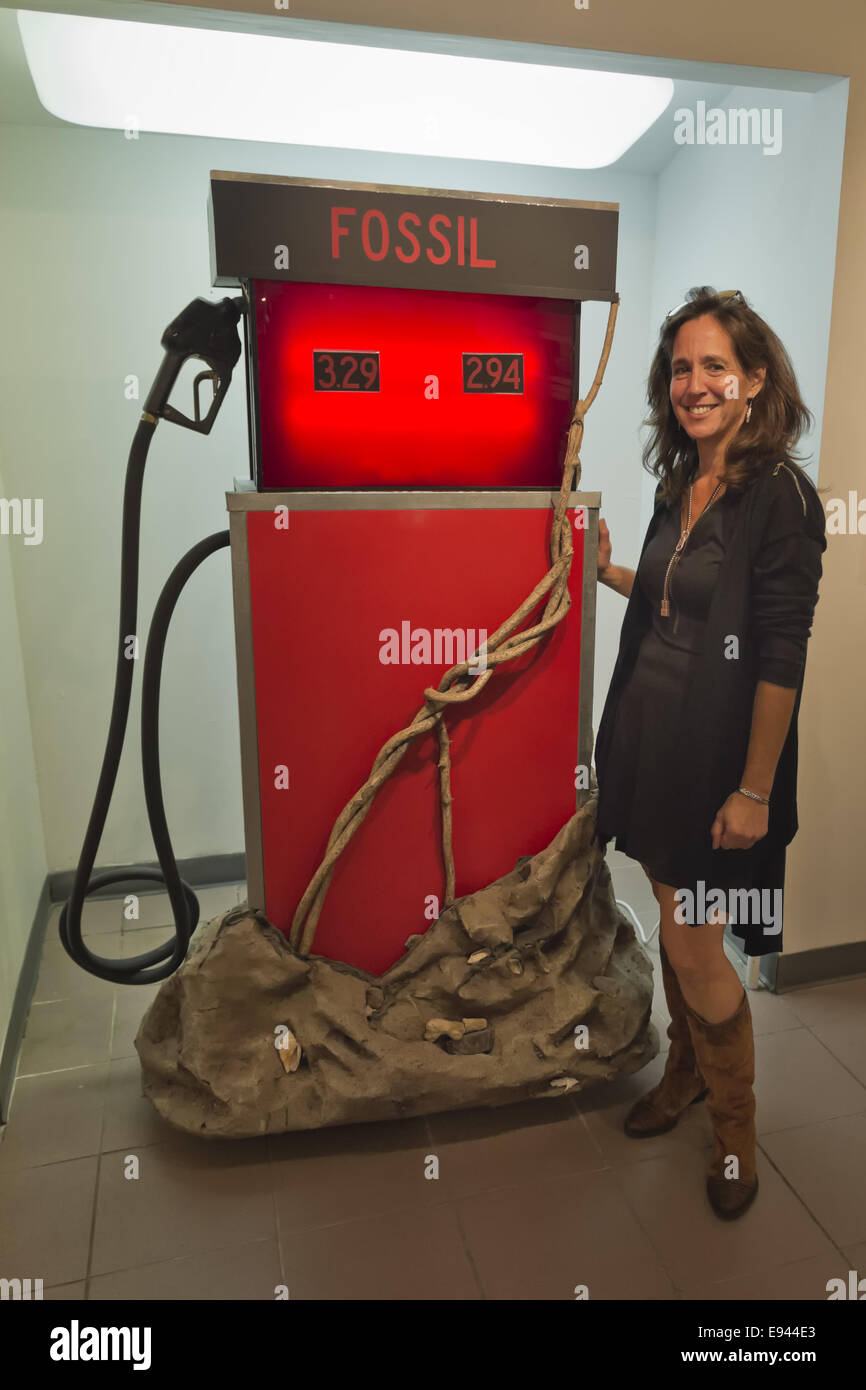Massapequa, New York, USA. 18th Oct, 2014. LORI HOROWITZ, artist and gallery owner, is standing next to her sculpture Distilled Life, a glowing red gas pump with FOSSIL written at top, during the Studio 5404 Art Space opening reception for the art show Taking it to the Street. Environment is the theme of the mixed media installation, which is made of wood, plastic, and paper mache, and the exhibit features new works by emerging and up-and-coming local and New York artists. Studio 5404 is on the South Shore of Long Island. Credit:  Ann Parry/ZUMA Wire/Alamy Live News Stock Photo