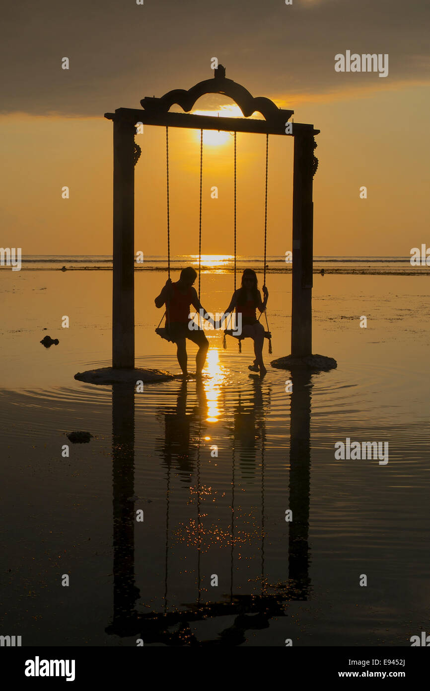 Sunset with couple in sea swing Gili Trawangan Lombok Indonesia Stock Photo