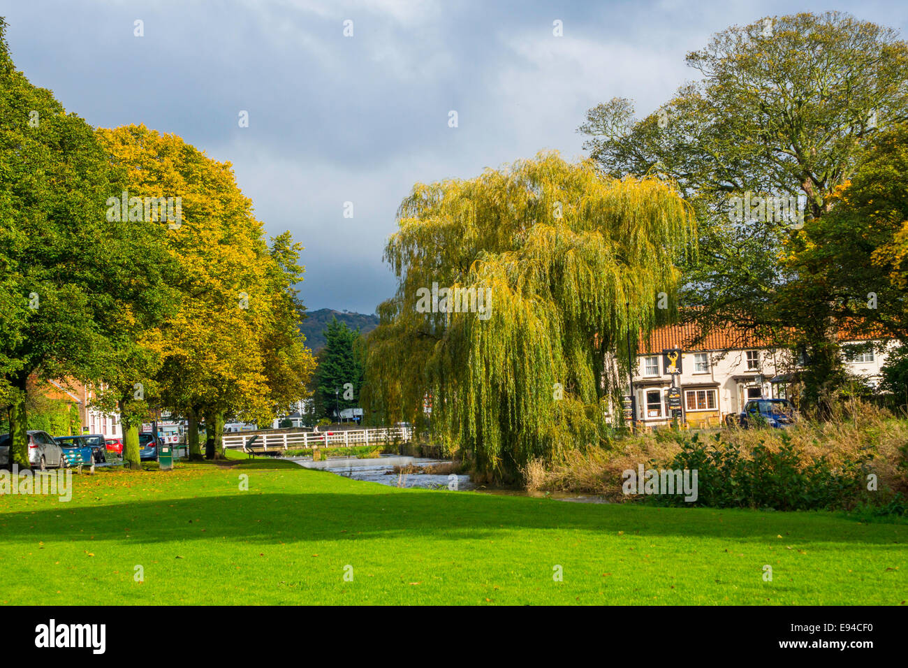 Footbridge over the river Leven to the Buck Inn in autumn sunshine on the village green Great