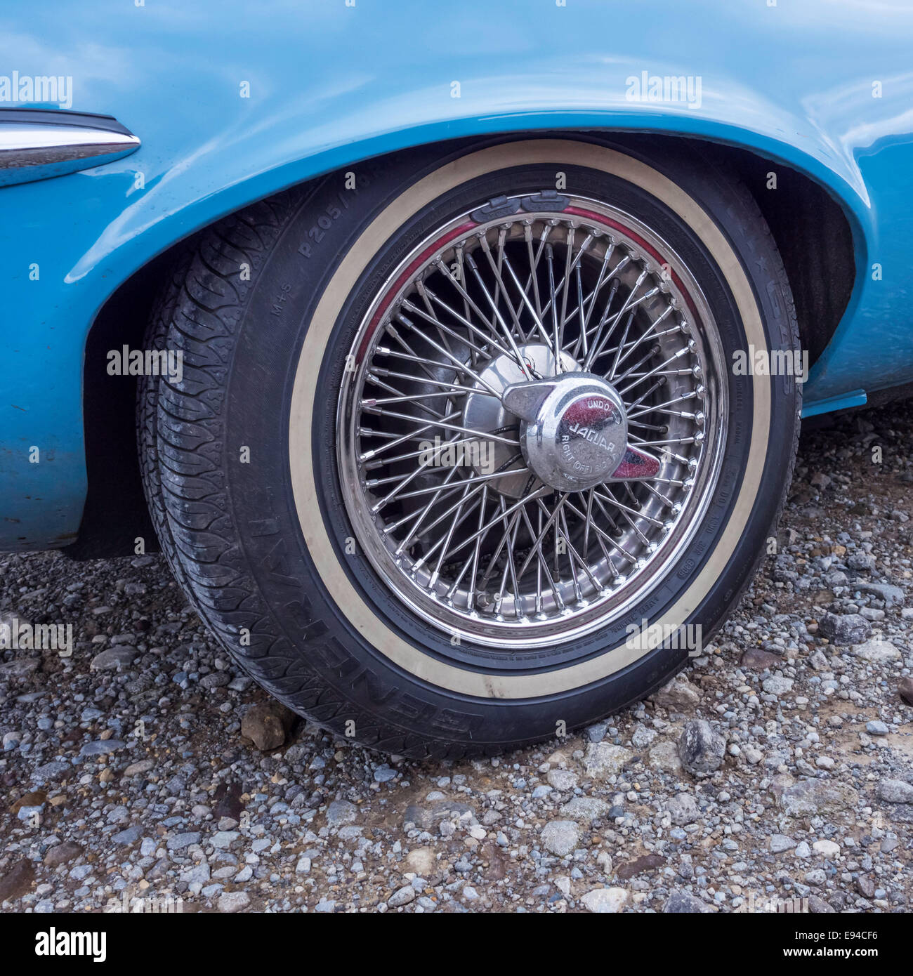 Offside wire spoke rear  wheel with knock-off hub cap blue 1971/72 Jaguar E-type roadster motor car Stock Photo