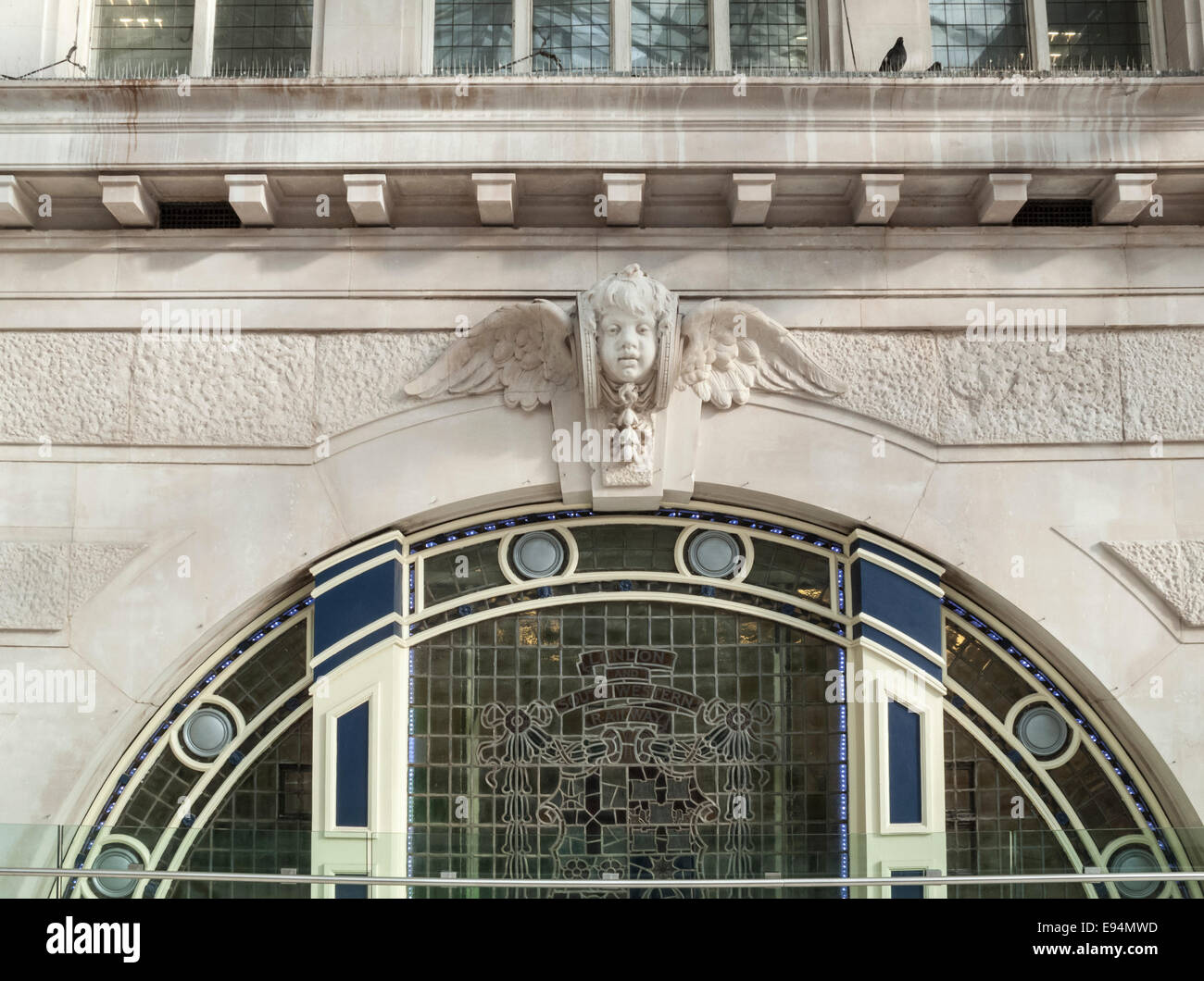 Decorative stone carving of a winged cherub above a now-closed doorway entrance in London Waterloo station, UK's busiest railway station Stock Photo