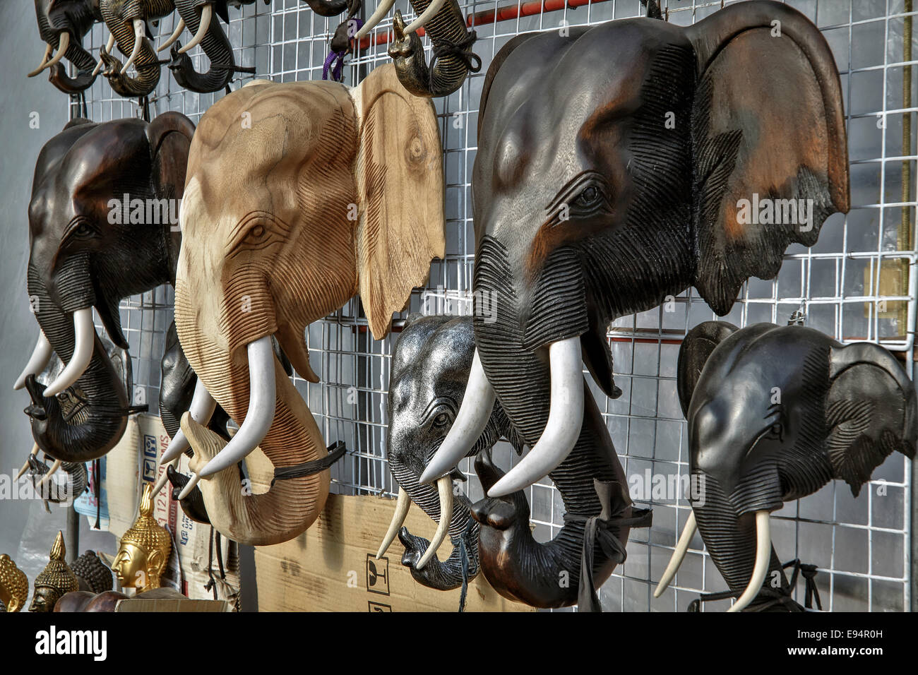 Intricately carved wooden elephant heads for sale on a Thai market stall. Thailand S. E. Asia Stock Photo