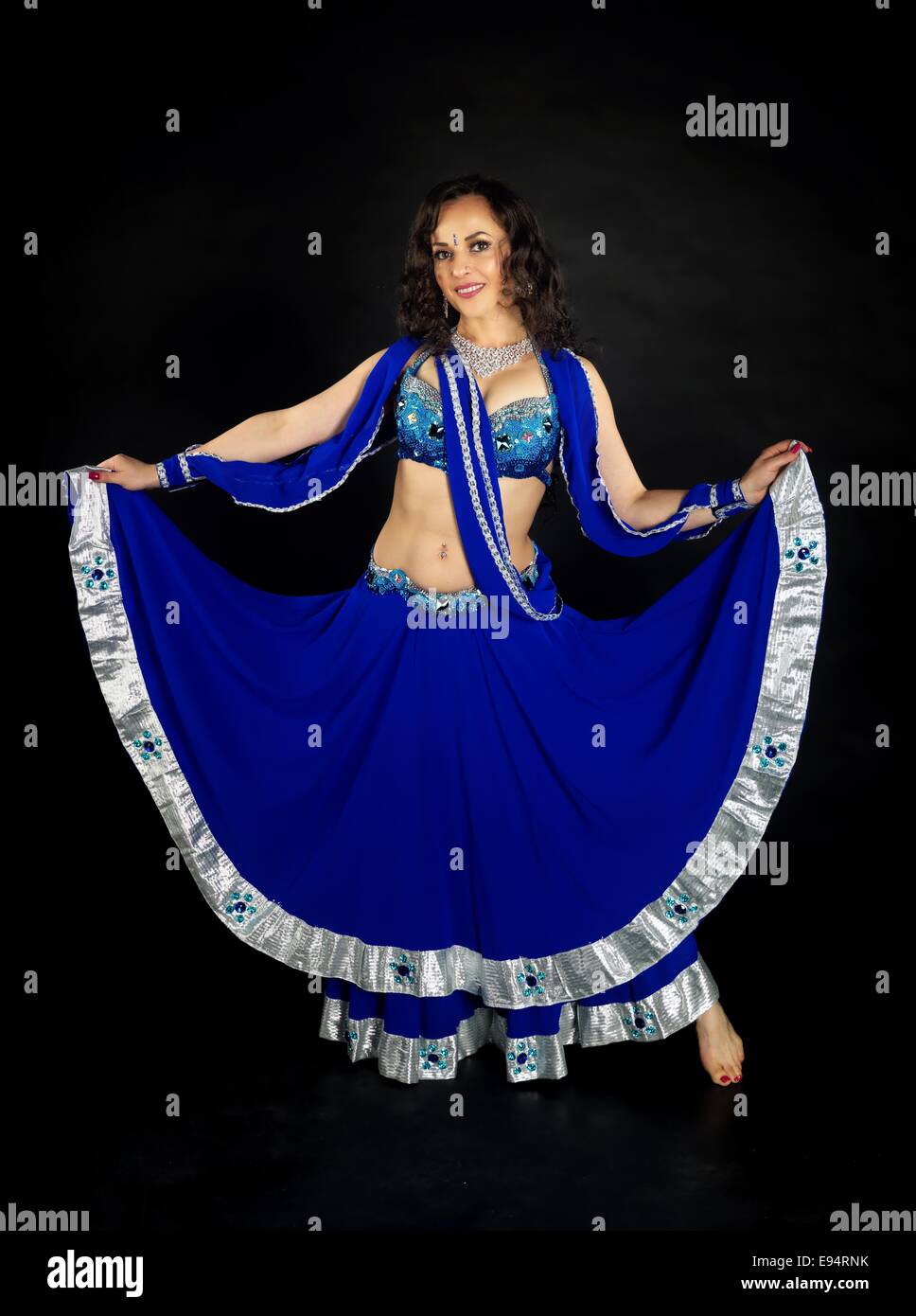 Young beautiful belly dancer wearing dark blue costume in front of the