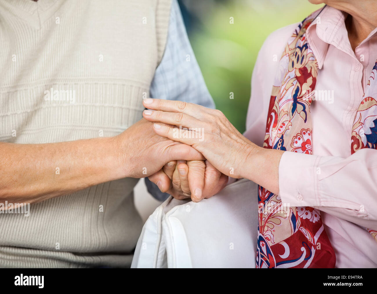 Senior Couple Holding Hands While Sitting On Chairs Stock Photo