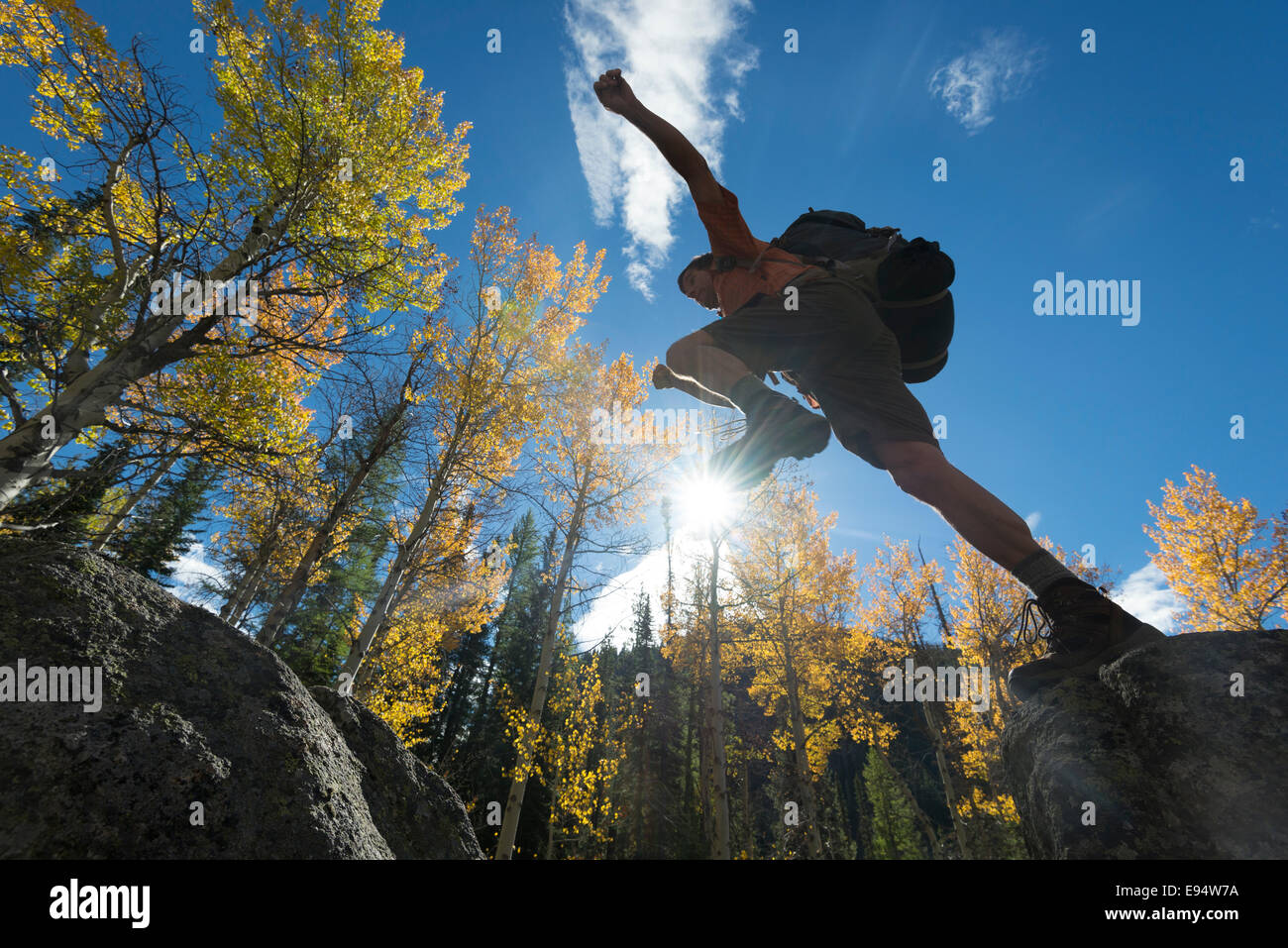 Backpacker leaping from boulder to boulder on a talus slope in Oregon's Wallowa Mountians. Stock Photo
