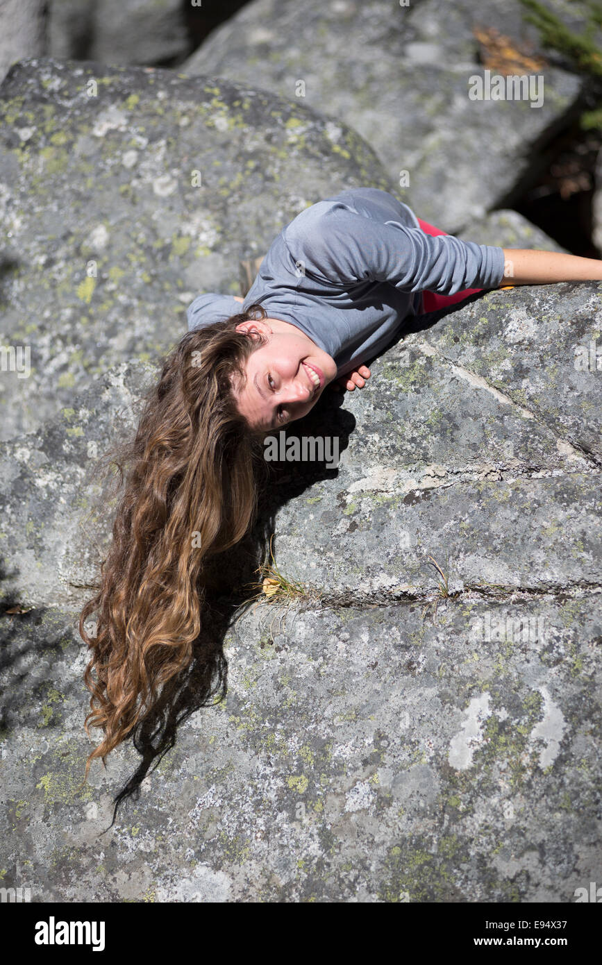 Woman hanging over boulder, Wallowa Mountains, Oregon. Stock Photo