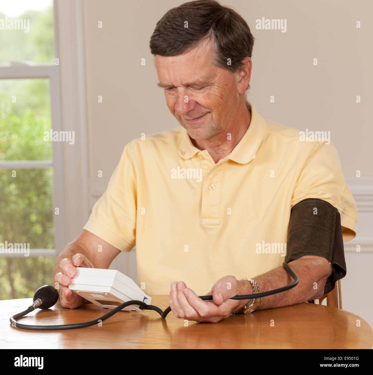 Senior man taking blood pressure at home Stock Photo