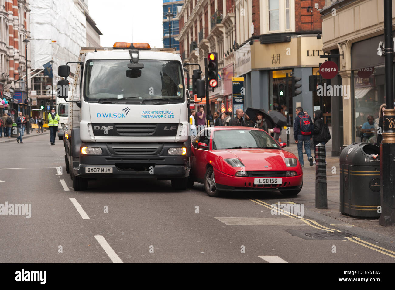 Shaftesbury Lane brought to a standstill as a scaffolding lorry shunts a parked red car on double yellow lines into a steel Stock Photo