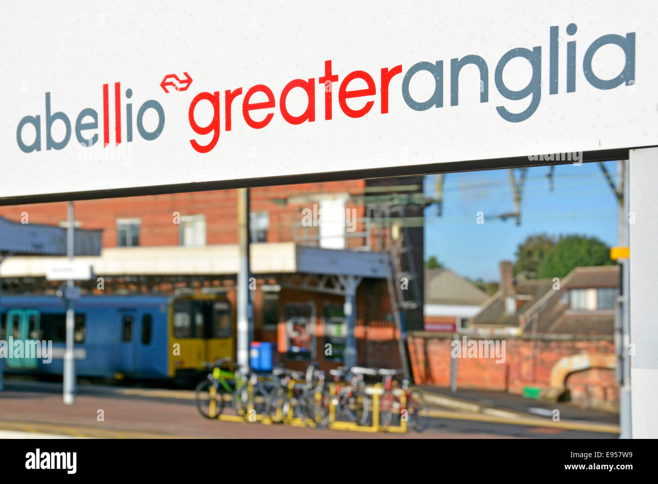 Abellio Greater Anglia brand name on railway station platform sign framing a Metro all stations train waiting to depart Stock Photo