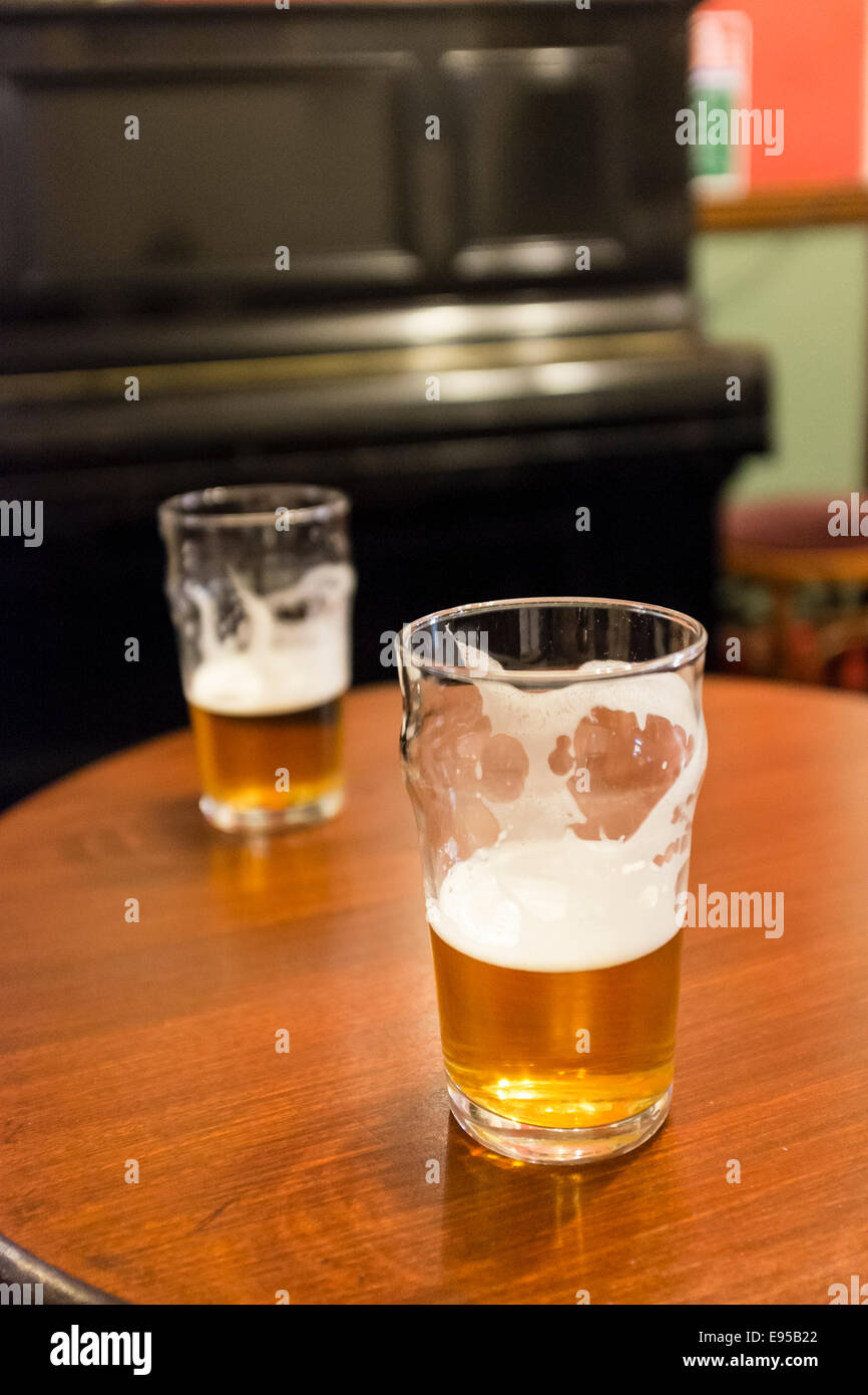Two beer glasses on a pub table in a traditional british pub Stock