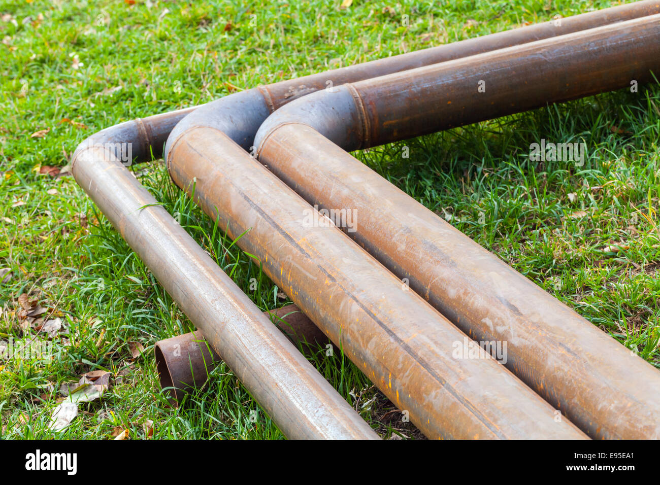 Bend of industrial outdoor steel pipeline over green grass Stock Photo