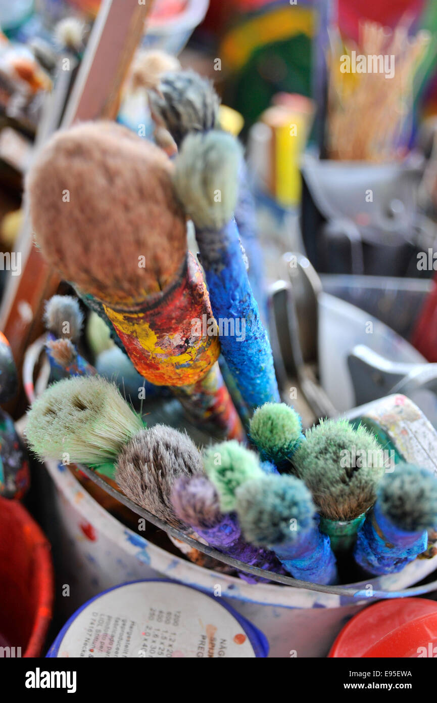 A collection of several artist's paintbrushes encrusted with different colour paint Stock Photo