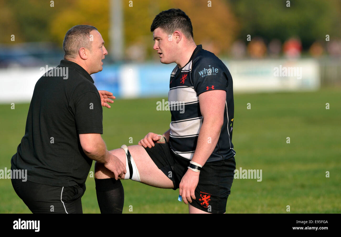 a coach attends an injured player during a match at broughton park rugby club, manchester, uk Stock Photo