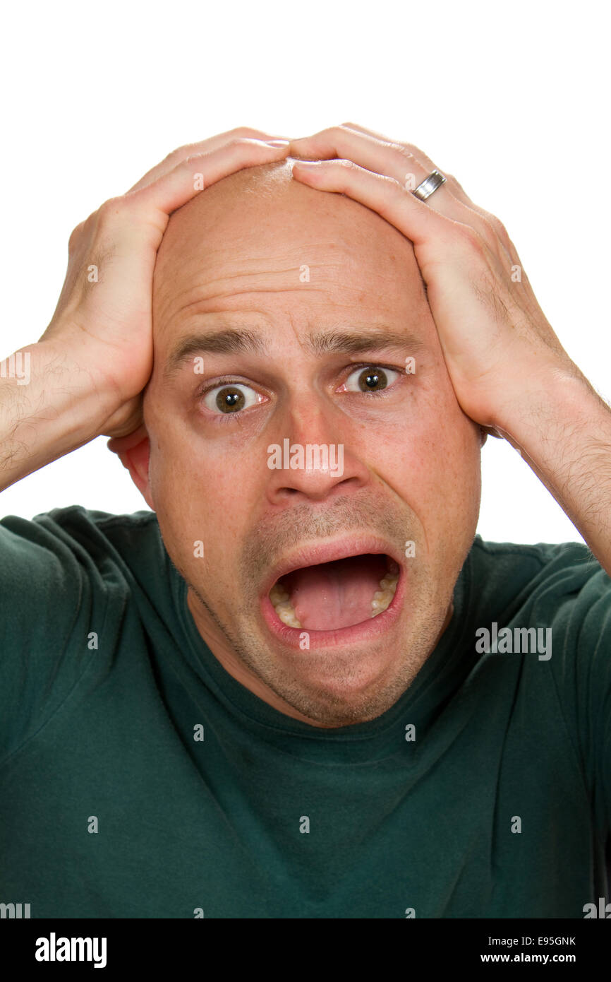 Man holds the top of his head with a frightened expression on his face. Stock Photo