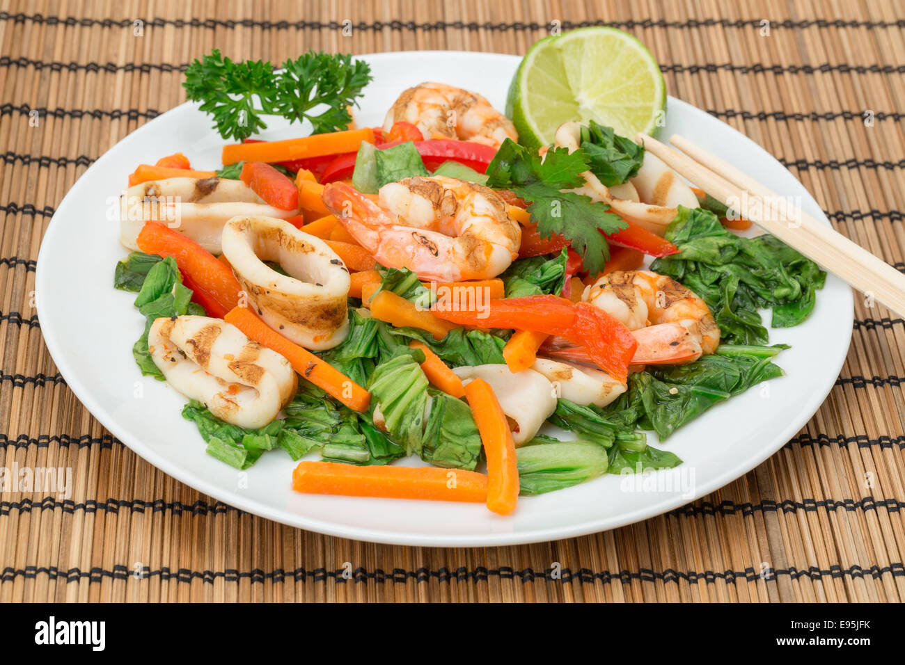 Vietnamese cuisine - plate of chargrilled Calamari and King Prawns with strips of carrot, red bell peppers, and pak choi Stock Photo