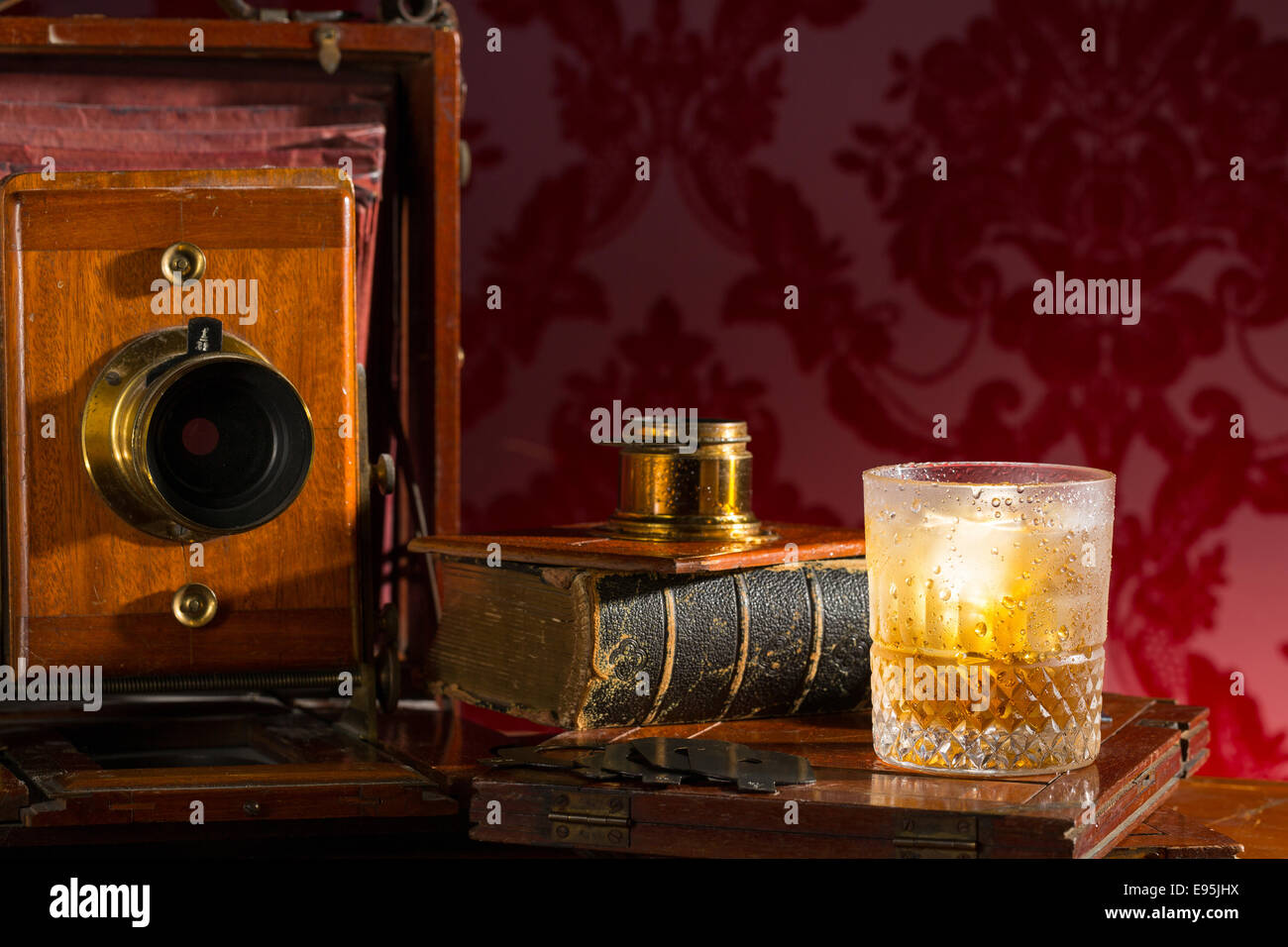 Old fashioned bellows plate camera still life with a glass of whiskey and ice Stock Photo