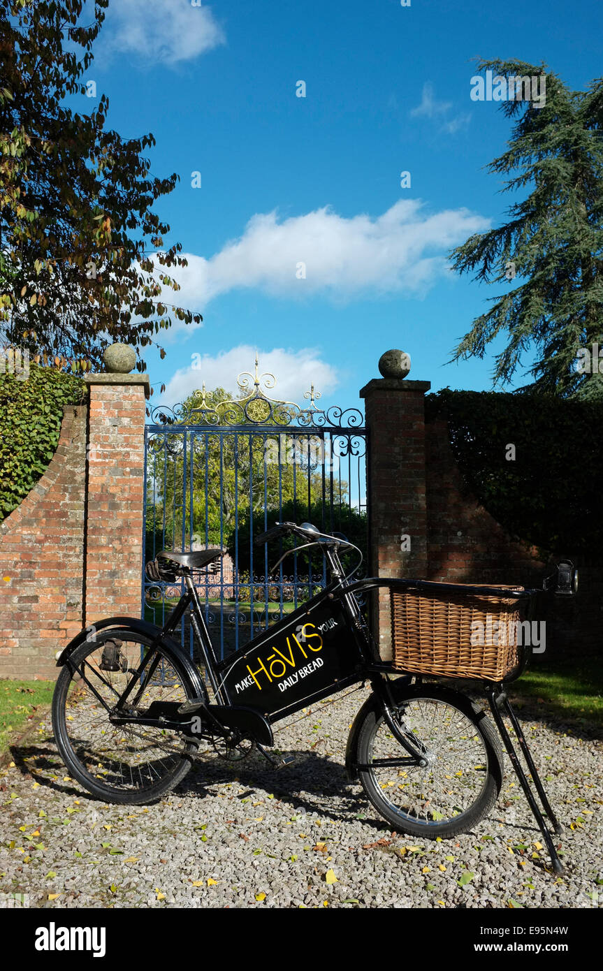 Vintage 1930's bakers (Tradesman's) delivery bicycle with wicker basket and old  sign writing Hovis advertising board. Stock Photo