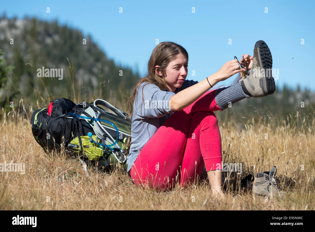 Woman putting on her hiking boots on a backpack trip in Oregon's