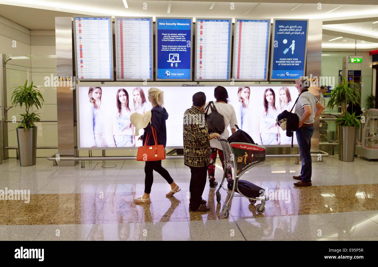 Air passengers looking at the Departure board, Dubai Airport Terminal, UAE, United Arab Emirates Stock Photo