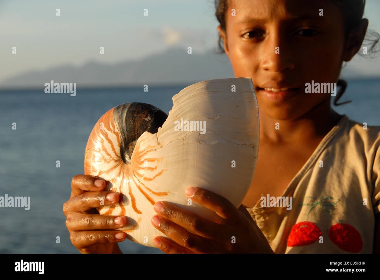 girl with big mollusc in hand at beach iat Flores in indonesia Stock Photo