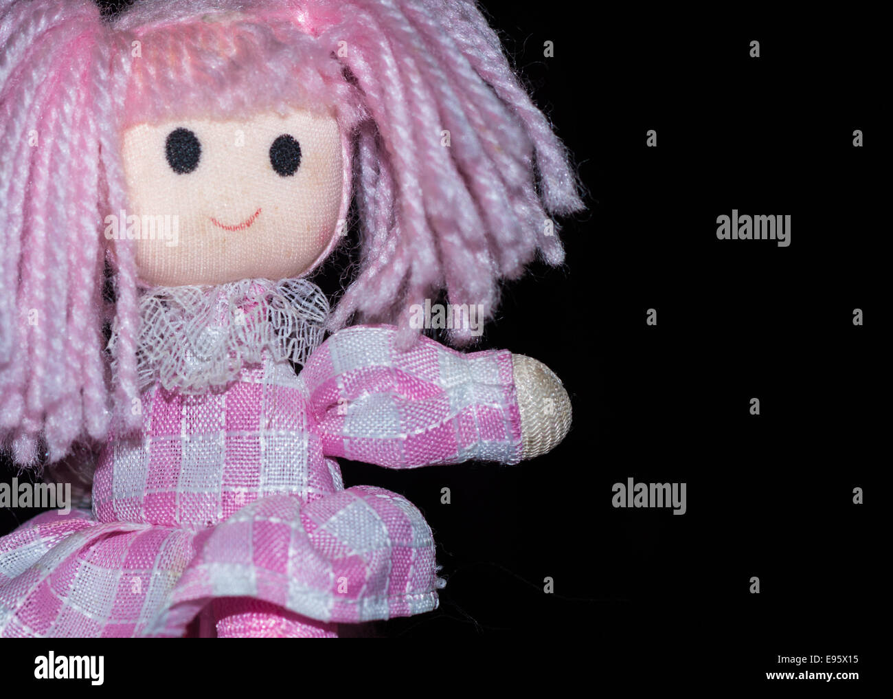 Pink patchwork wool doll pen pointing on a plain black background. Stock Photo
