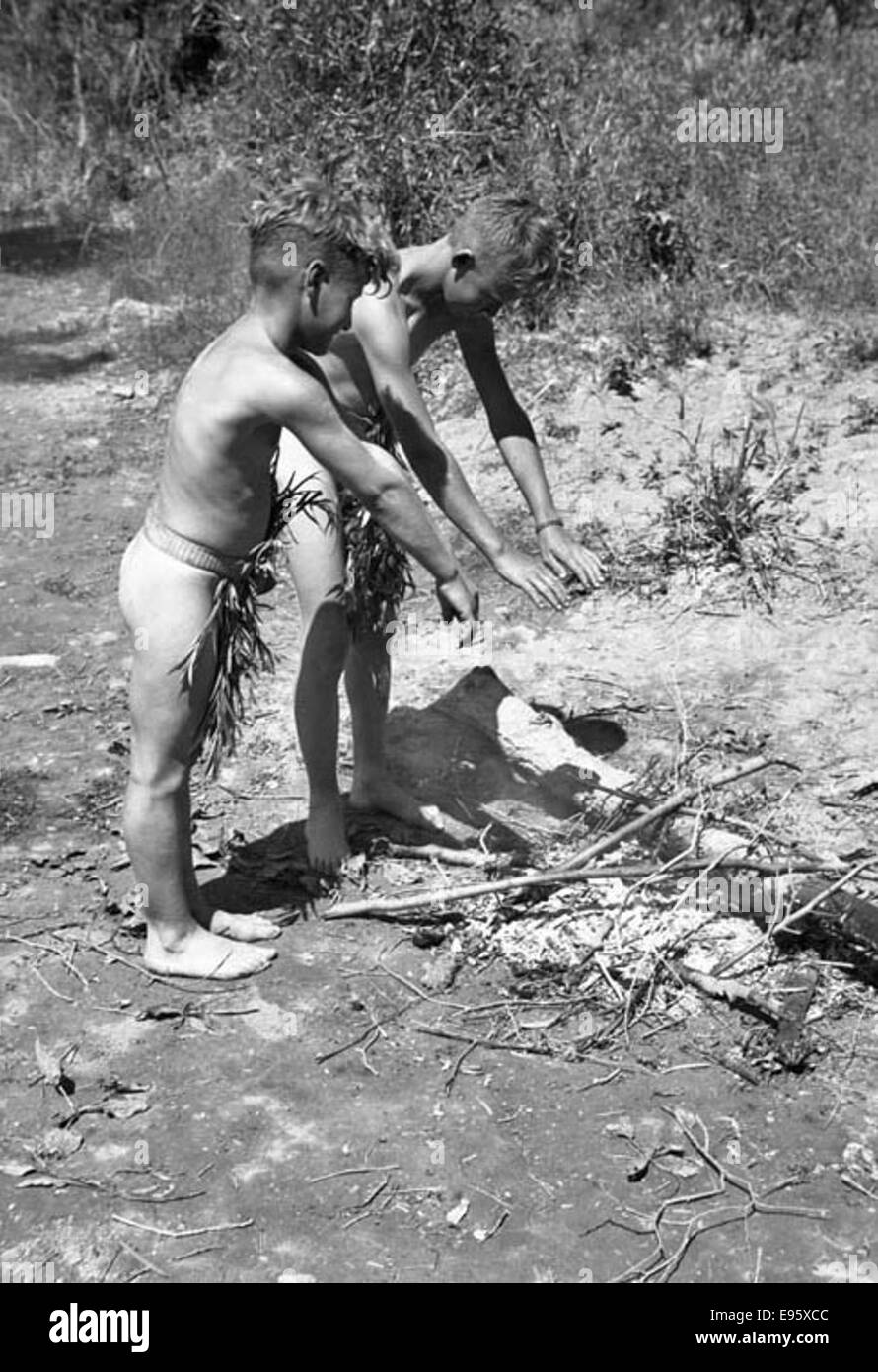 Two boys dressed in ‘loin cloths' play by the fire (ACROSS THE RIVER) 2 July 1948 21/4 x 31/4 negative This is one of 54 photos in the album “Fort Macleod’s Anonymous”. Most are shot in Fort Macleod, Alberta in Stock Photo