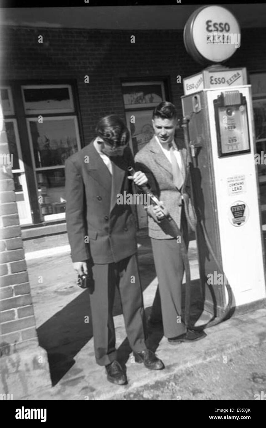 Two young men examining a fuel hose at Esso gas station. March 1948 21/4 x 31/4 negative This is one of 54 photos in the album “Fort Macleod’s Anonymous”. Most are shot in Fort Macleod, Alberta in the late 1940s. Stock Photo