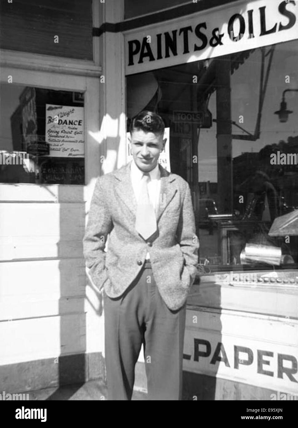 A young man posing in front of a store window; sign “Paints &amp; Oils” behind. March 1948 21/4 x 31/4 negative This is one of 54 photos in the album “Fort Macleod’s Anonymous”. Most are shot in Fort Macleod, Stock Photo