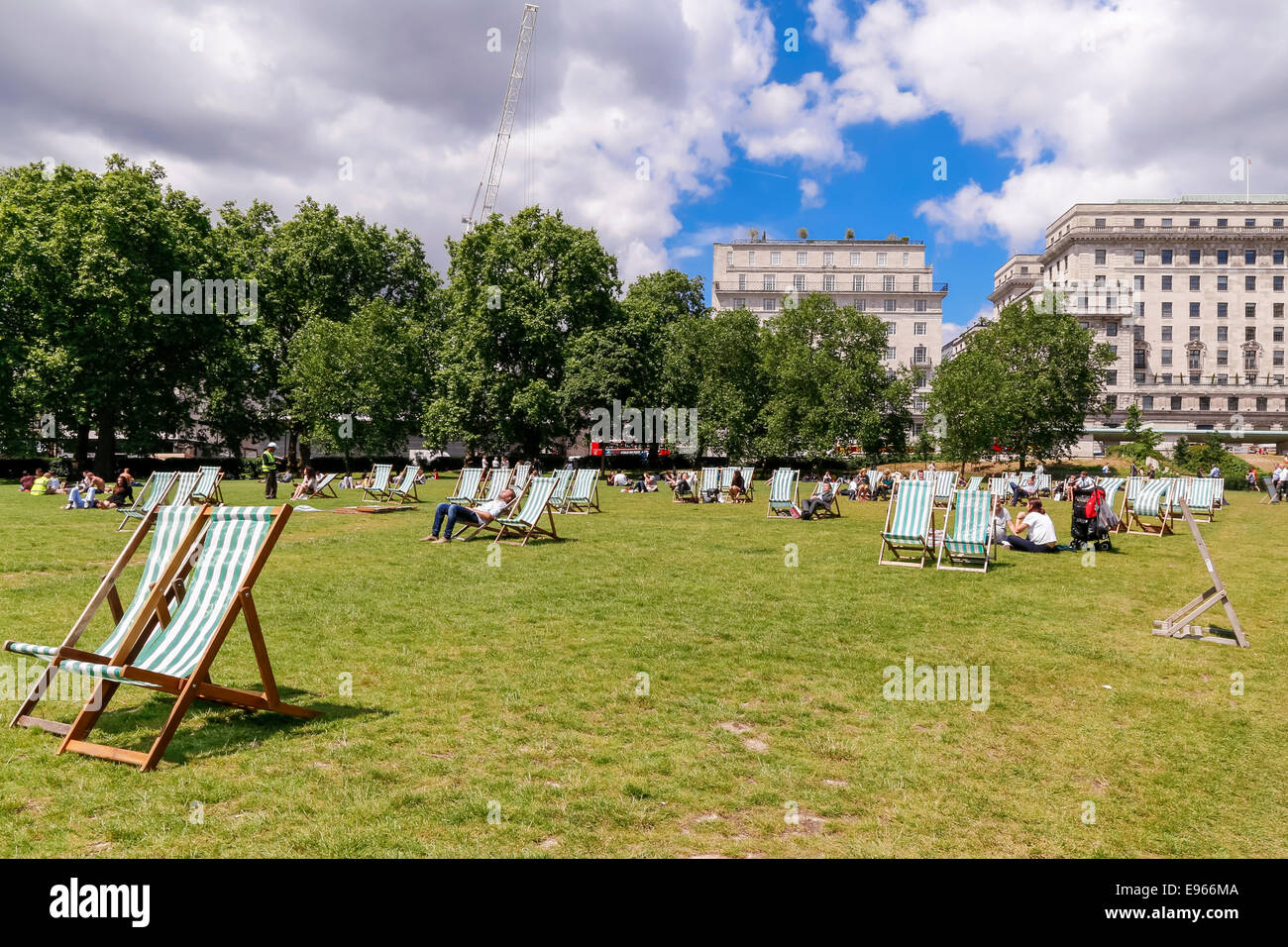 People enjoying sunshine, striped canvas deckchairs in Green Park