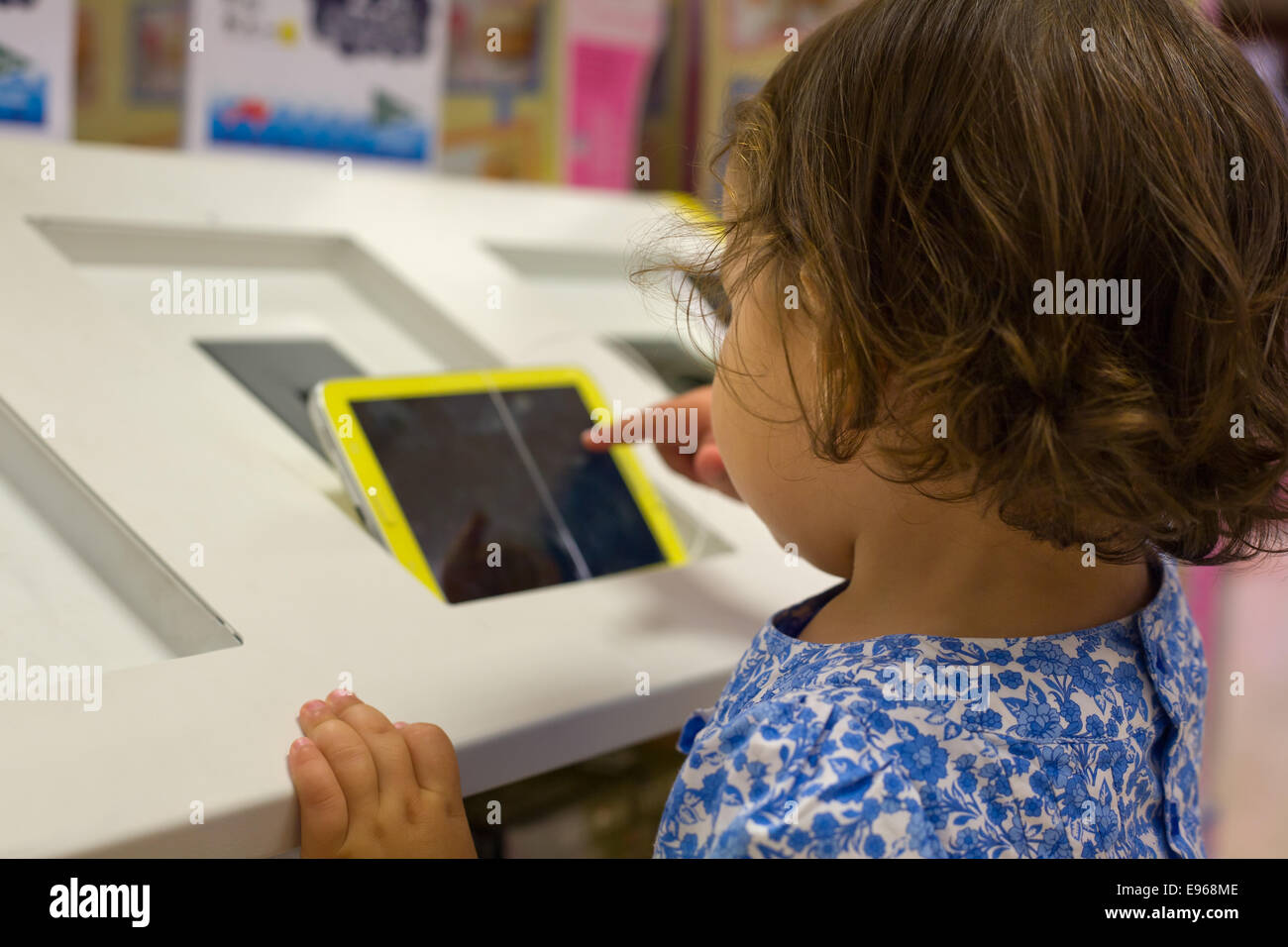 Baby girl playing with a digital tablet on a big shopping center Stock ...