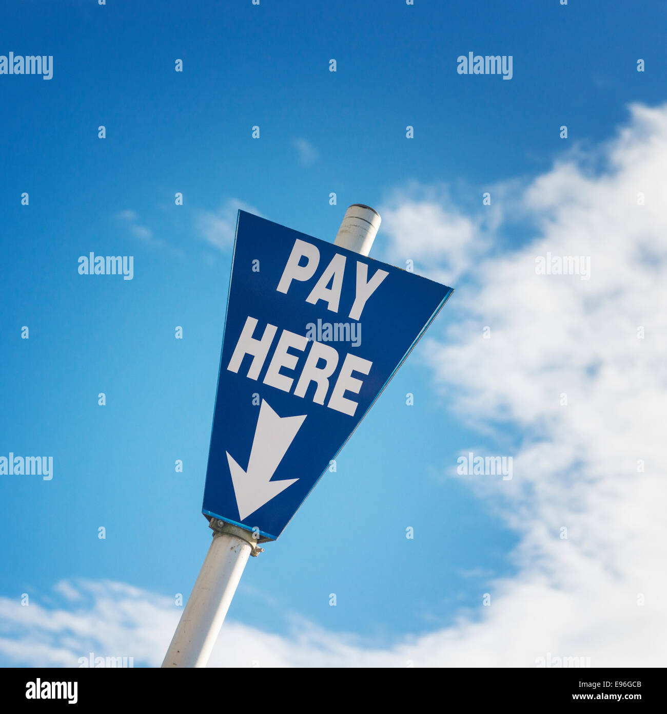 A pay here sign in a car park against a blue sky. Stock Photo