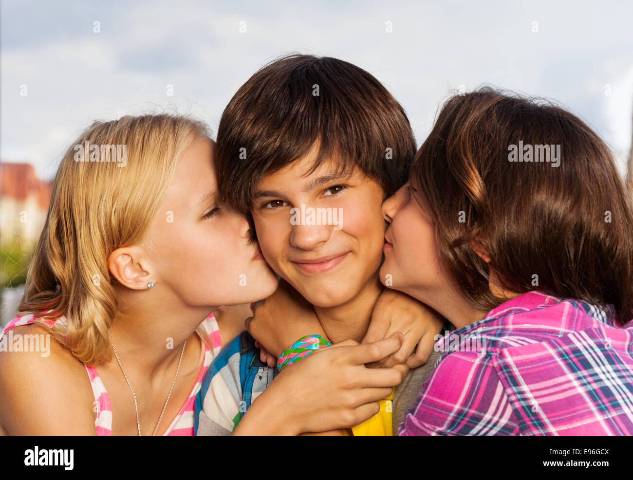 Two girls kiss boy in cheeks close up view Stock Photo