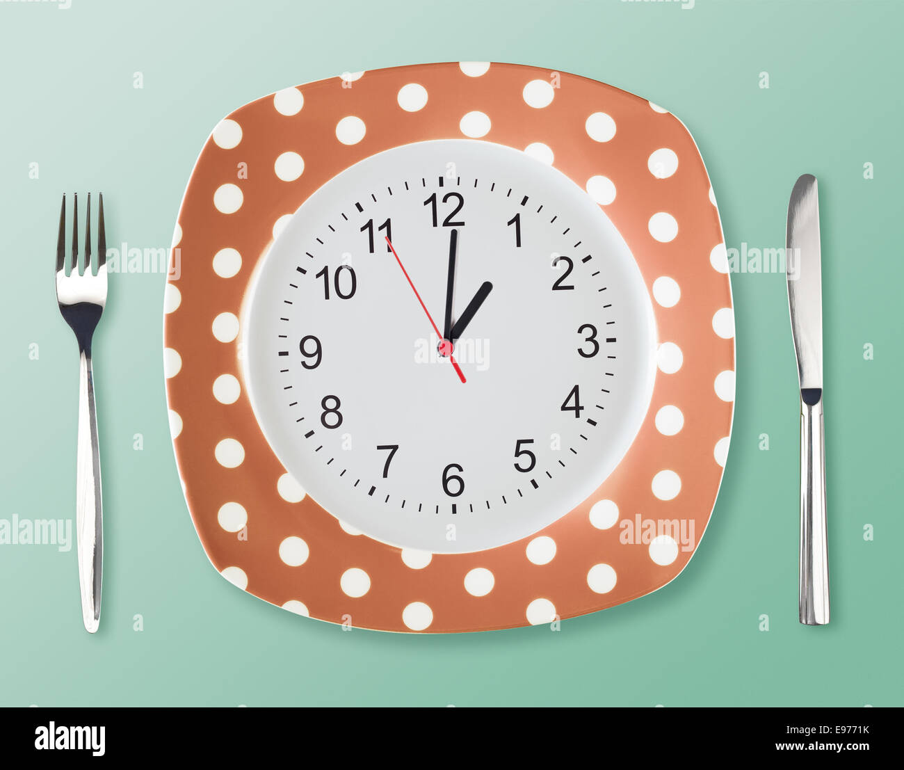 Dinner plate retro style with clock face fork an tableknife Stock Photo