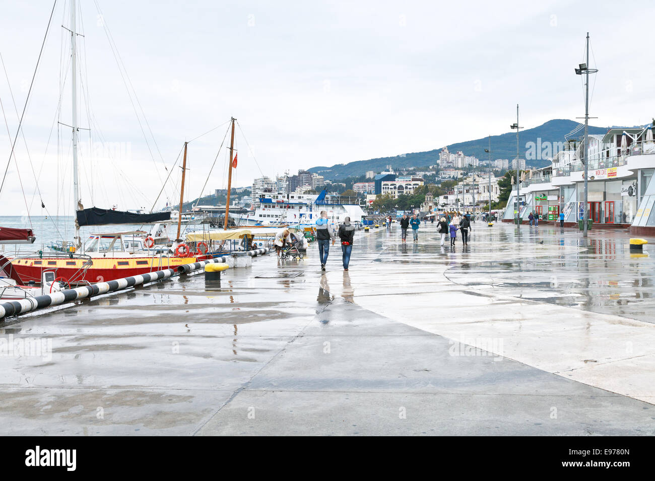 YALTA, RUSSIA - SEPTEMBER 27, 2014: tourists on Lenin embankment in Yalta city in rainy day. Yalta is resort city on the north c Stock Photo