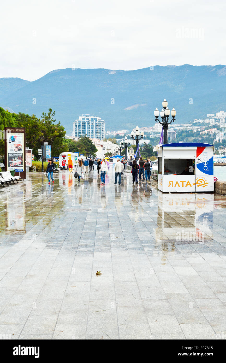 YALTA, RUSSIA - SEPTEMBER 27, 2014: tourists walk on Lenin embankment in Yalta city in rainy day. Yalta is resort city on the no Stock Photo