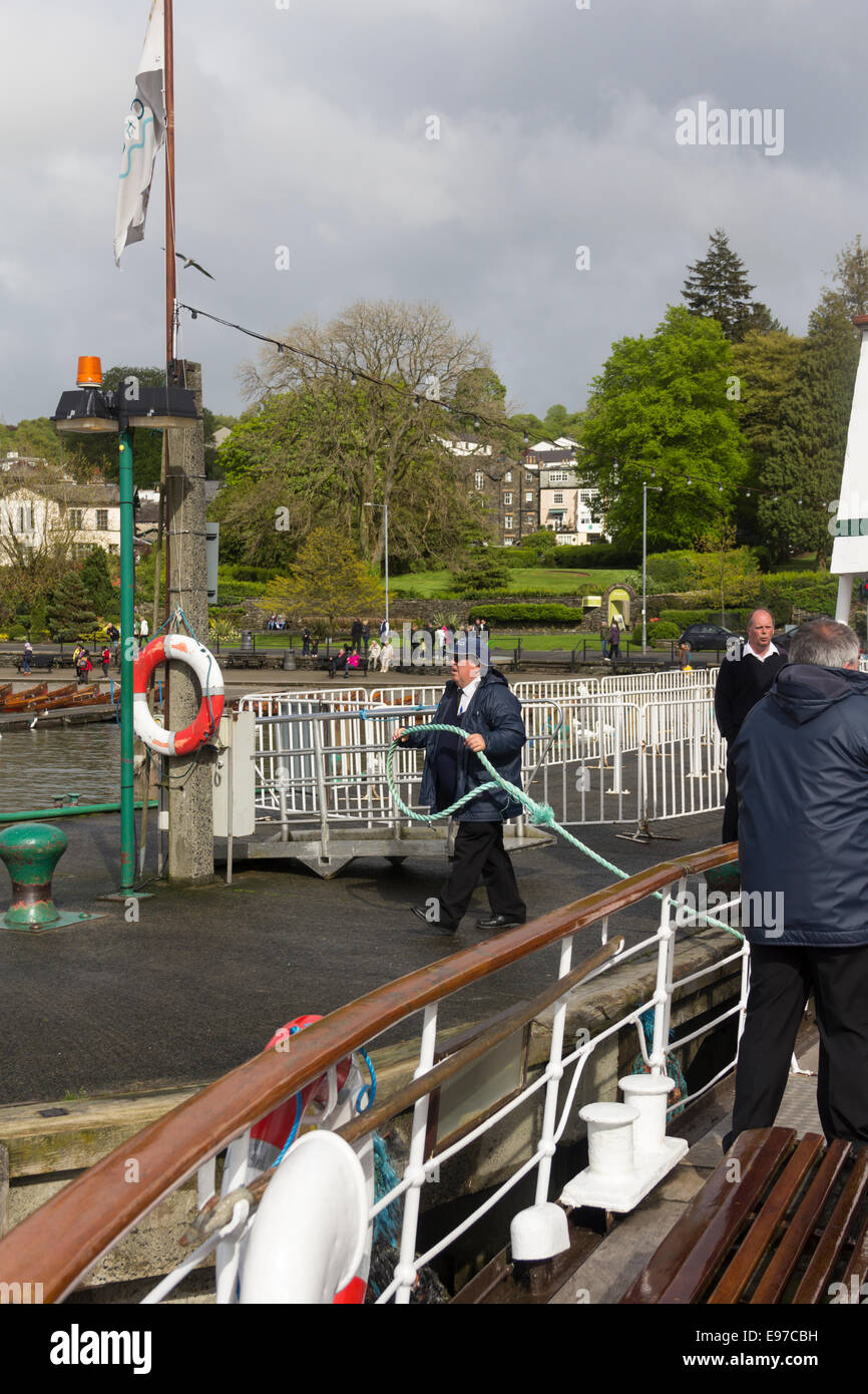 A member of the pier staff takes the mooring rope of Lake Windermere steamer MV Swan as she arrives at Bowness-on-Windermere in the Lake District. Stock Photo