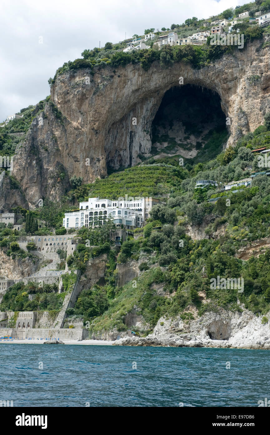 A large cave, villas, olives and lemons on the cliffs close to Amalfi from a boat in the Bay of Salerno in May Stock Photo
