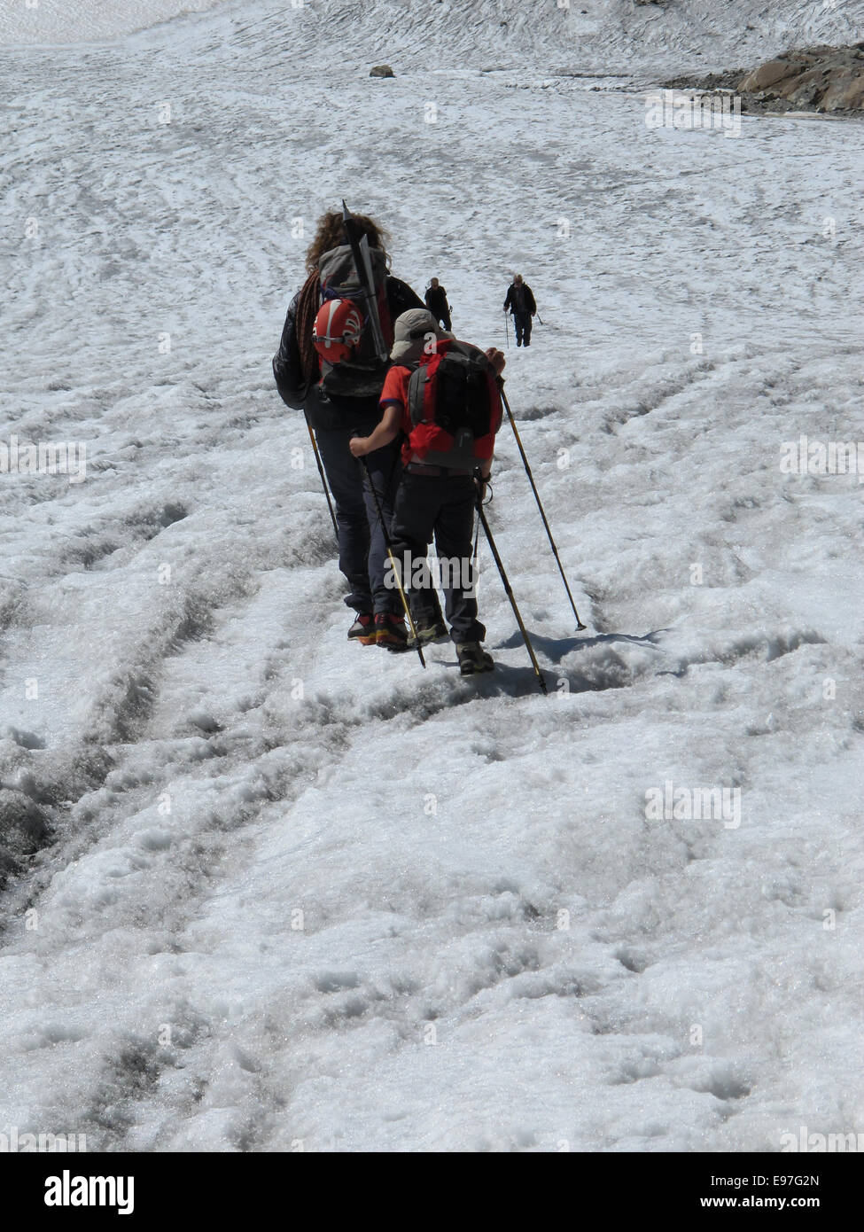 Mountain guide leading his young client across a crevasse covered glacier Stock Photo
