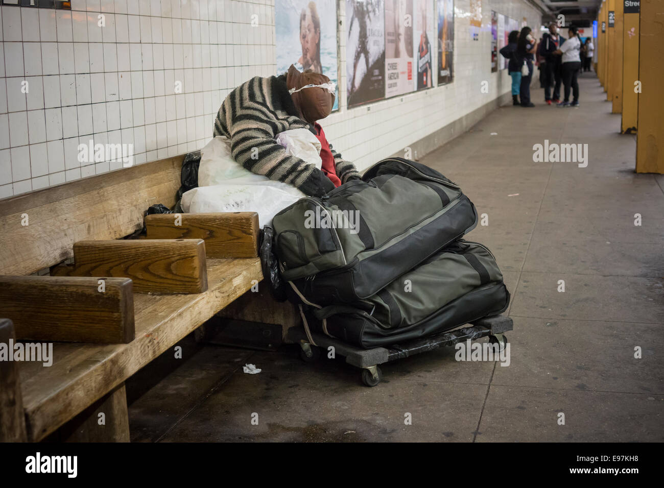 An un-domiciled individual sleeps on a subway platform in New York Stock Photo