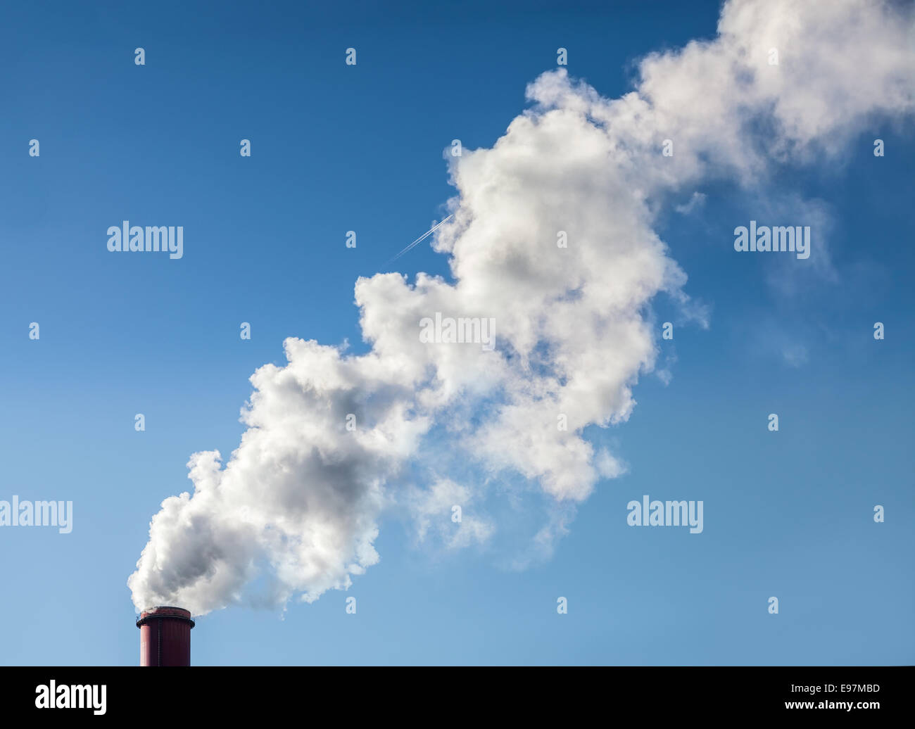 Smoke from industrial smokestack on a clear blue sky. Stock Photo