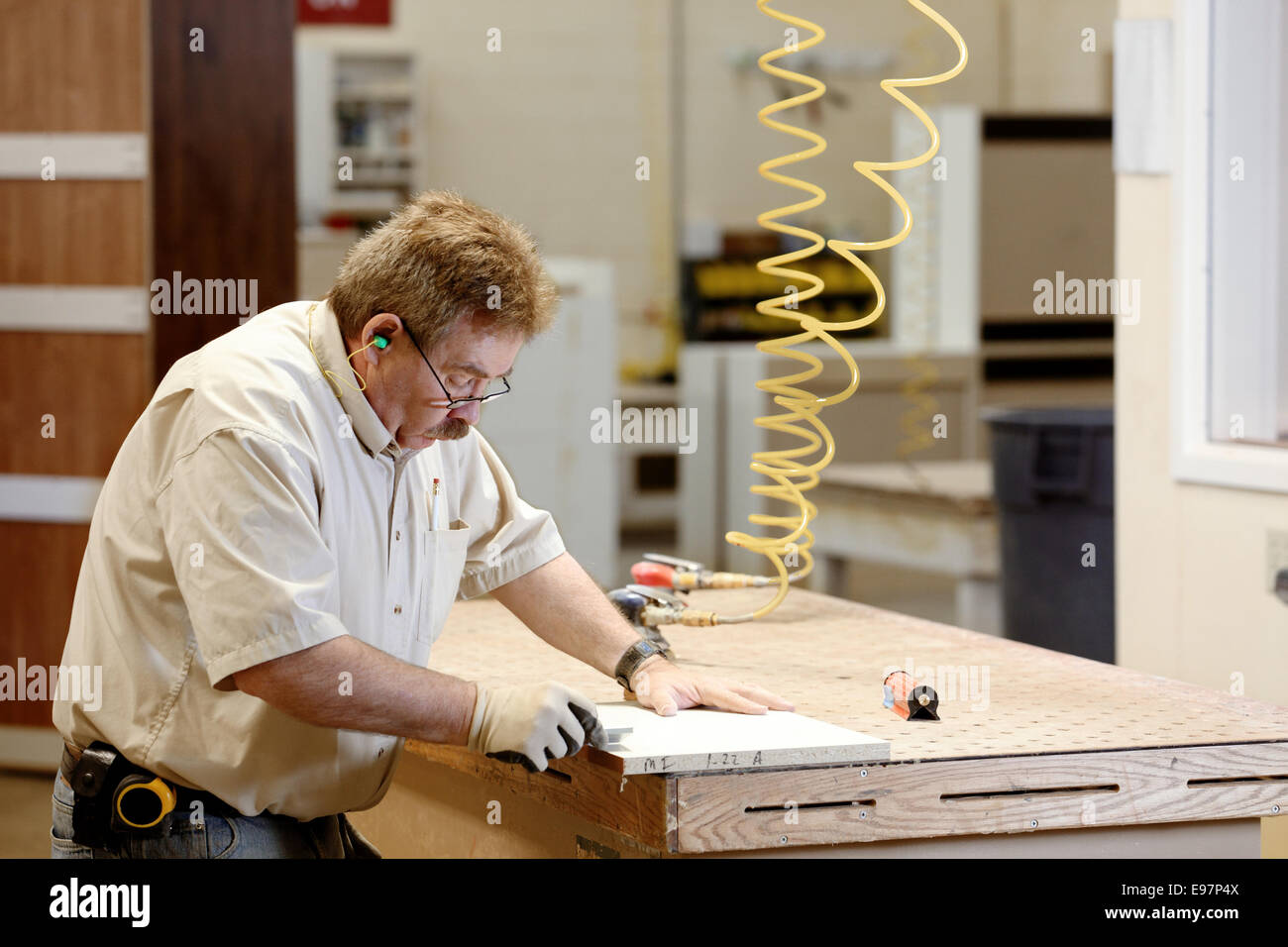 A carpenter trimming the edge banding of new cabinet doors. Stock Photo