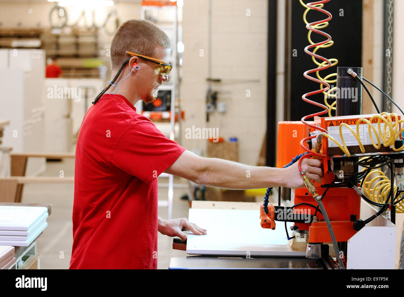 A carpenter using a line boring machine to drill shelf peg holes in the